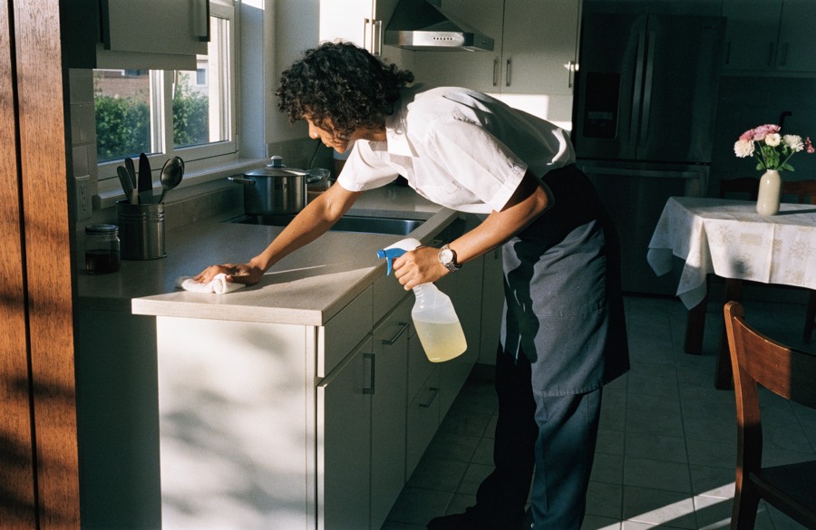 Cleaner wiping down a kitchen worktop