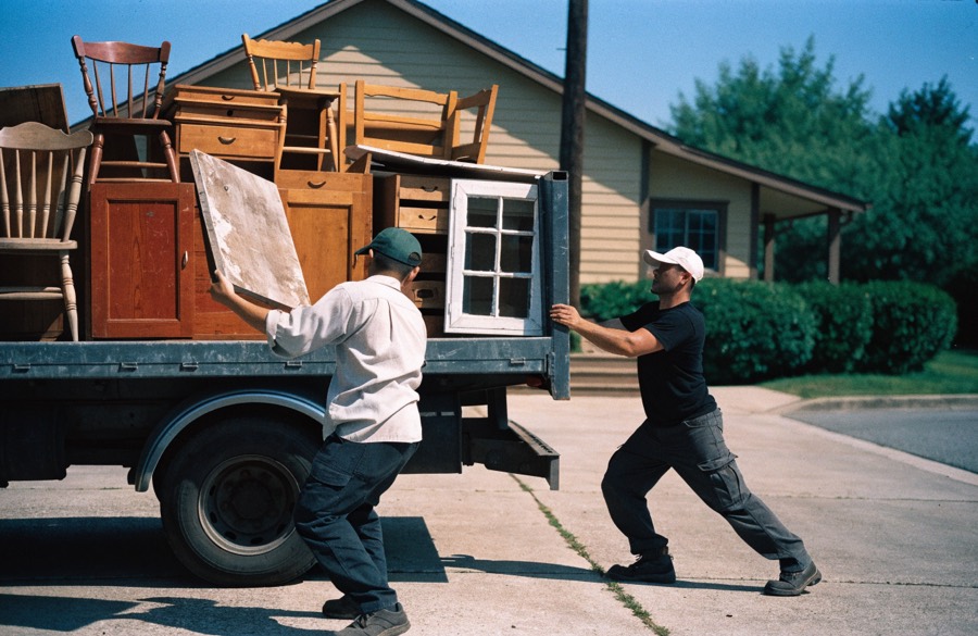 Workers loading waste onto a truck in a driveway